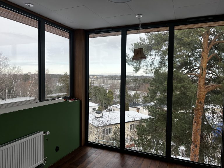 Höga glaspartier med mörka profiler och utsikt över träd