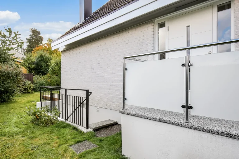 Glasräcke med frostat glas vid en entré till ett vitt hus
